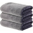 Three folded grey PrimeBuild microfiber gym towels stacked on a white background, folded edges facing the camera