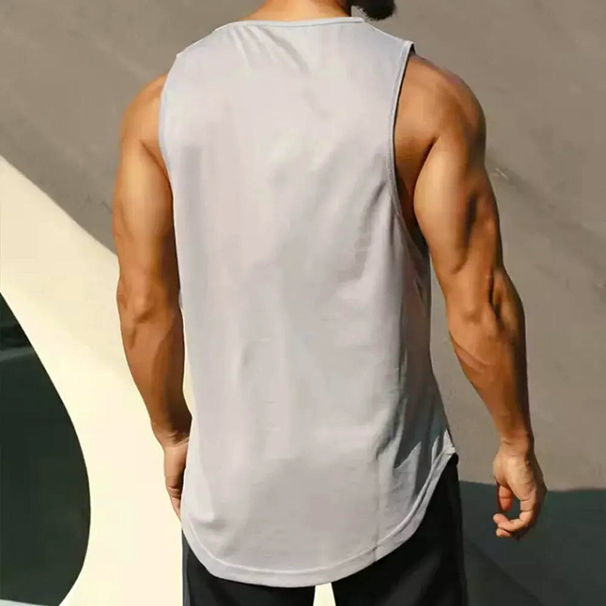 PrimeBuild Men's Quick-Dry Running Tank in grey, back view on a model showing the sleeveless cut and curved hem