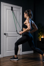 PrimeBuild Door Anchor Pulley atop a light gray door, holding a green resistance band with a handle for a split-stance row