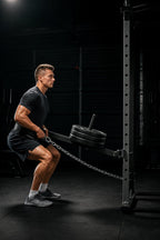 PrimeBuild Landmine Attachment mounted on a power rack, loaded with plates, while a lifter does a belt squat