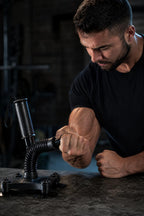 Man bending the PrimeBuild Arm Wrestling Wrist Trainer spring handle sideways on a dark stone tabletop