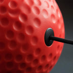 PrimeBuild Boxing Reflex Ball close-up showing the red dimpled surface and where the black elastic cord attaches