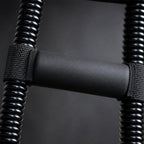 Close-up of the PrimeBuild Wrist Strengthener foam stabilizer pad strapped between the black coiled springs