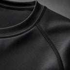 Close-up of the PrimeBuild Men's Long Sleeve Performance Shirt in black showing the crew neck and raglan shoulder seam
