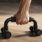 Close-up of a hand gripping the foam handle of a PrimeBuild Push-Up Bar with glossy black frame on a wood floor