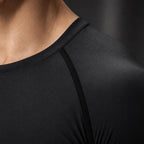 Close-up of the PrimeBuild Men's Compression Training Shirt in Black showing the crew neck and raglan shoulder seam