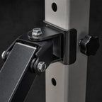 Close-up of the PrimeBuild Landmine Attachment black pivot bracket and locking knob on a power rack upright