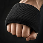 PrimeBuild Boxing Gel Knuckle Guard in black ribbed knit worn over the knuckles of a closed fist on a dark background