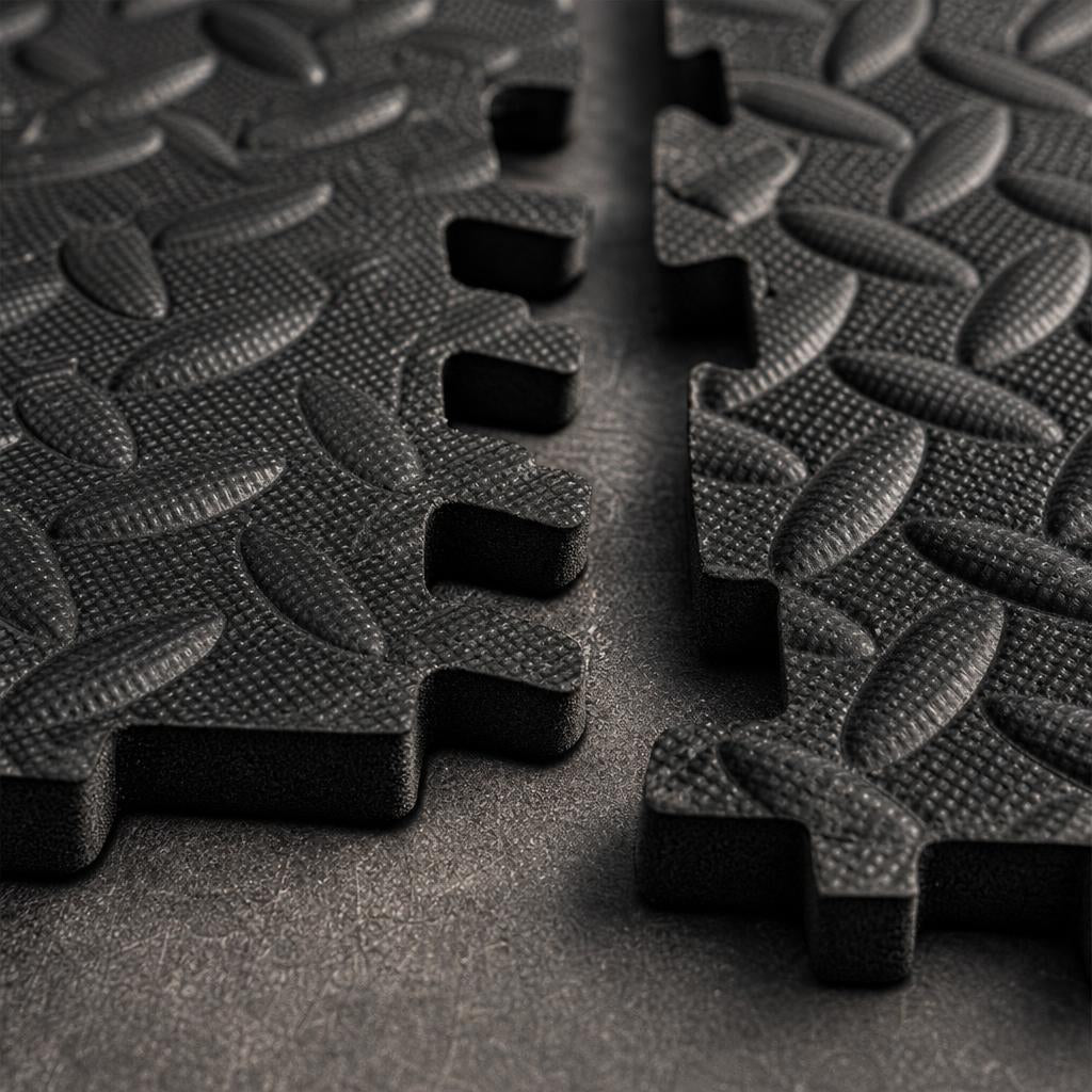 Close-up of PrimeBuild Interlocking Foam Gym Mat tiles showing black puzzle edges and diamond plate texture