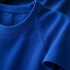 Close-up of the PrimeBuild Essential Training Tee in blue: crew neck collar, raglan seam and stitched sleeve hem