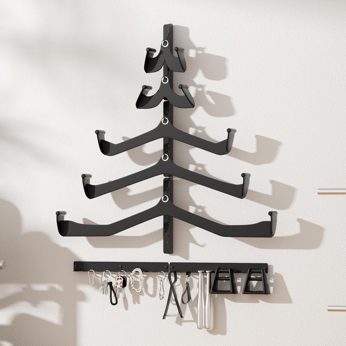 T-shaped wall rack installed on a wall holding bars on its curved arms and small accessories on the hook strip below