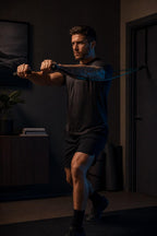 Man doing a standing chest press at home with PrimeBuild resistance band handles and a band anchored at a door