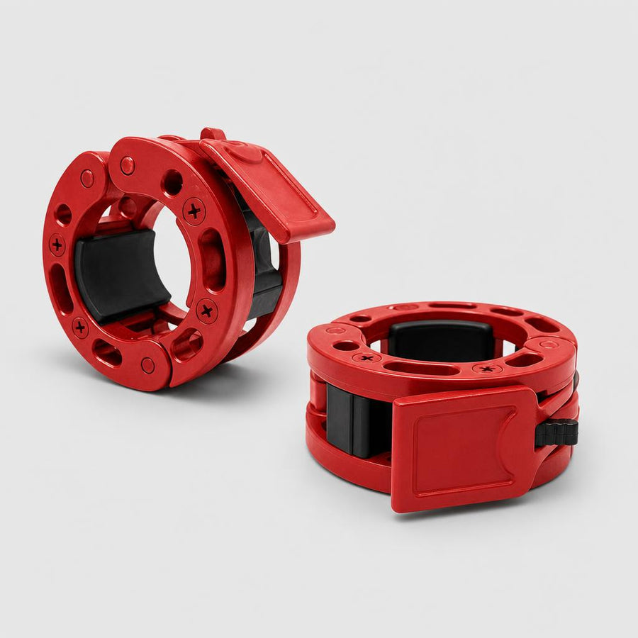 Two red PrimeBuild Olympic Barbell Collars with black inner lining, one with its lever open and one lying flat with it closed