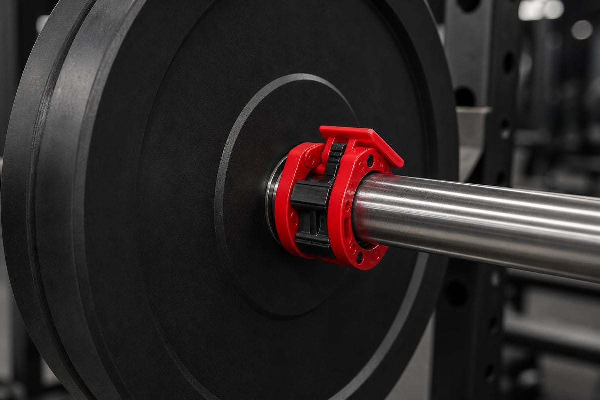 Red PrimeBuild Quick-Release Olympic Barbell Collar on a steel barbell sleeve, pressed against a black weight plate