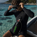 Snorkeler fitting a dive mask on a boat with the DEDEPU mini scuba tank in its sling bag