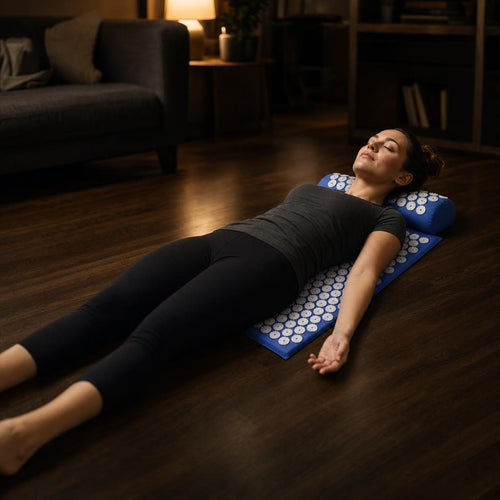 PrimeBuild Acupressure Mat & Pillow Set in Blue, woman lying on the mat with her neck on the pillow on a wood floor