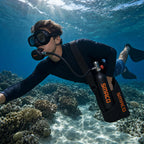 Snorkeler breathing from the SMACO S400 mini scuba tank over a shallow coral reef